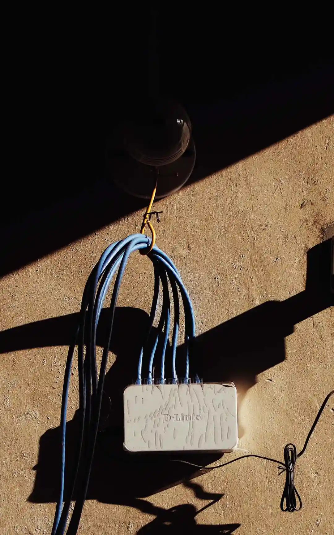 Outdoor network cable hanging from a wall hook into a weatherproof junction box